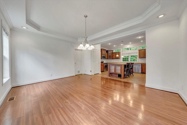 unfurnished living room with a chandelier, light hardwood / wood-style floors, a raised ceiling, and crown molding