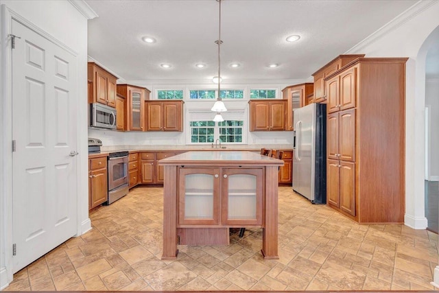 kitchen with ornamental molding, stainless steel appliances, sink, pendant lighting, and a center island