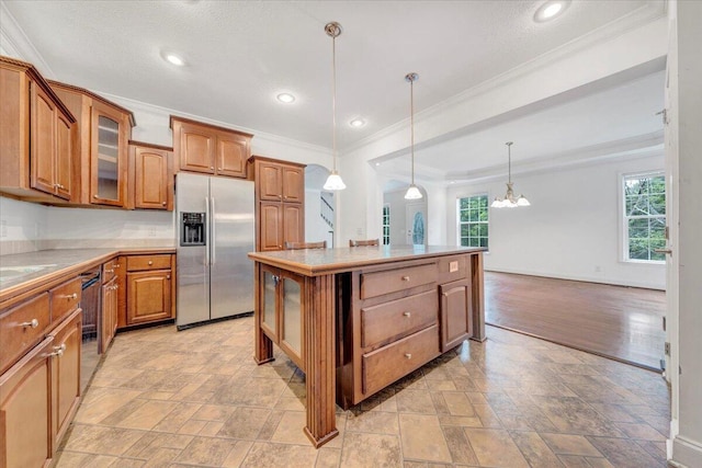 kitchen with hanging light fixtures, an inviting chandelier, stainless steel fridge, crown molding, and a kitchen island