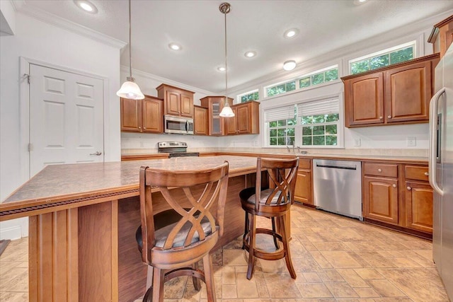 kitchen with stainless steel appliances, crown molding, pendant lighting, a kitchen island, and a breakfast bar area