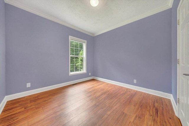 empty room featuring crown molding, hardwood / wood-style floors, and a textured ceiling