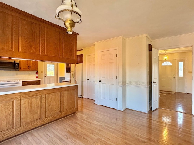 kitchen featuring light hardwood / wood-style flooring, white refrigerator with ice dispenser, crown molding, stove, and decorative light fixtures