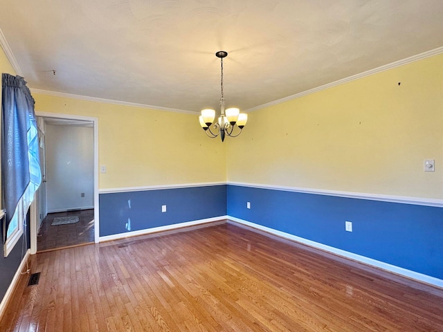 unfurnished room with hardwood / wood-style flooring, ornamental molding, and an inviting chandelier