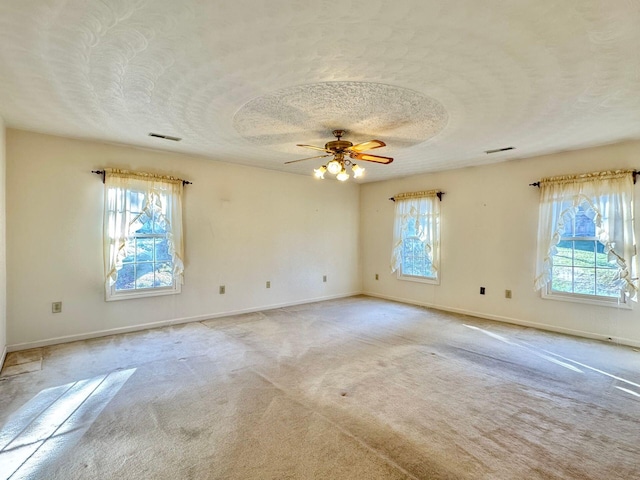 carpeted spare room featuring a wealth of natural light, ceiling fan, and a textured ceiling