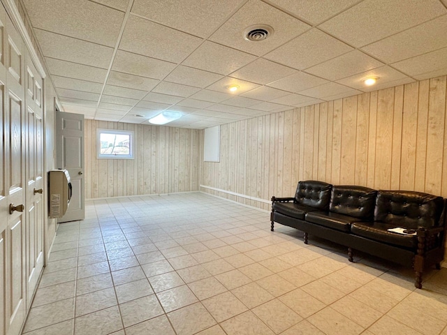 interior space with a paneled ceiling and wooden walls