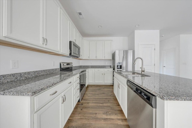 kitchen featuring dark wood-type flooring, sink, stainless steel appliances, light stone countertops, and white cabinets