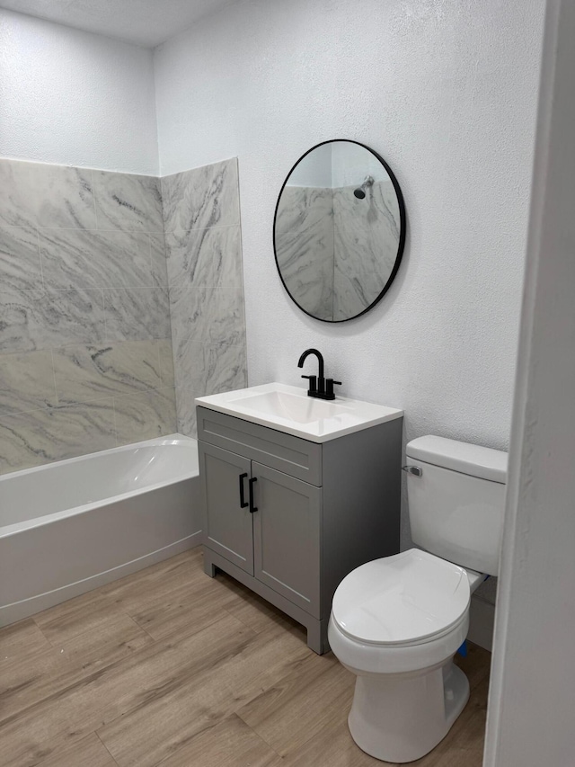 full bathroom featuring hardwood / wood-style floors, vanity, shower / bathtub combination, and toilet