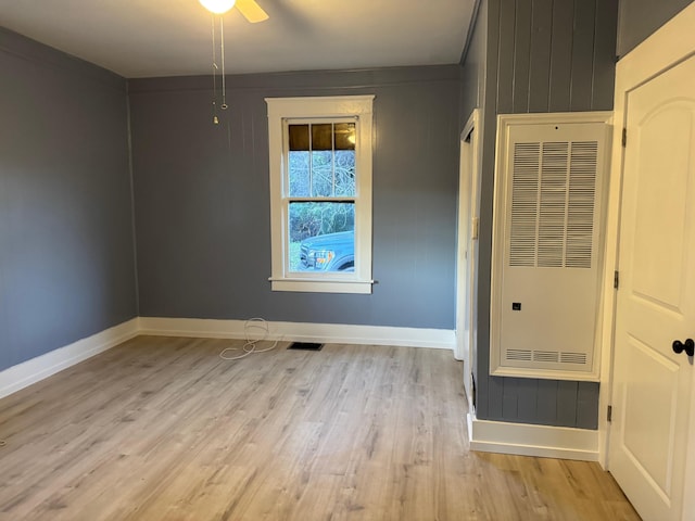 unfurnished room featuring light wood-type flooring, ceiling fan, and wooden walls