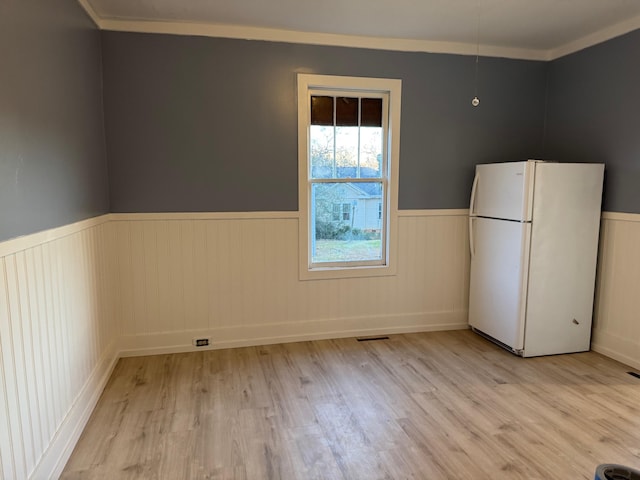 kitchen featuring white refrigerator, light wood-type flooring, and ornamental molding