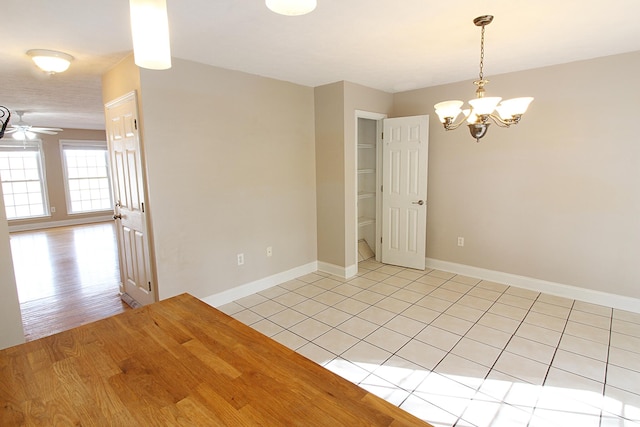 spare room with ceiling fan with notable chandelier and light hardwood / wood-style floors