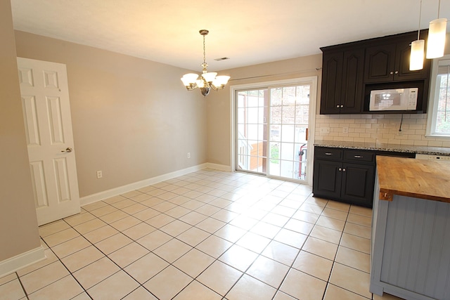 kitchen with wooden counters, a notable chandelier, decorative light fixtures, decorative backsplash, and light tile patterned floors