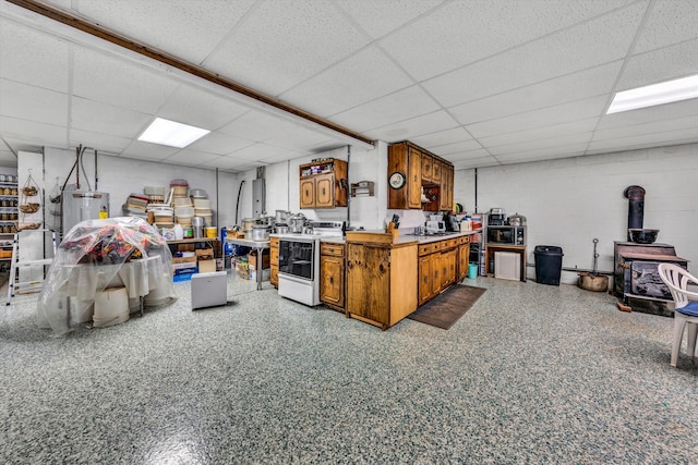 basement featuring a drop ceiling, a wood stove, sink, and water heater