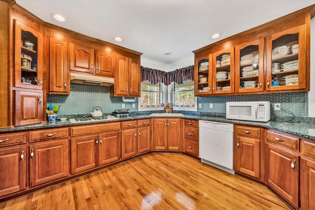 kitchen featuring decorative backsplash, dark stone countertops, white appliances, and light hardwood / wood-style flooring