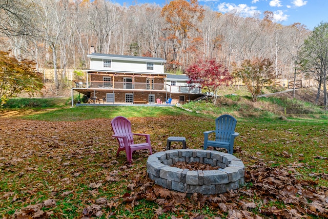 rear view of house featuring a fire pit, a yard, and a wooden deck