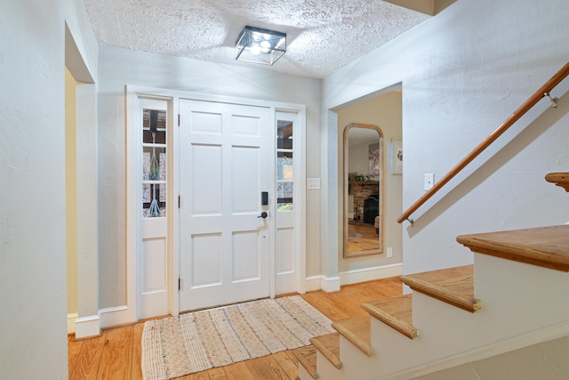 foyer with a textured ceiling and light hardwood / wood-style flooring