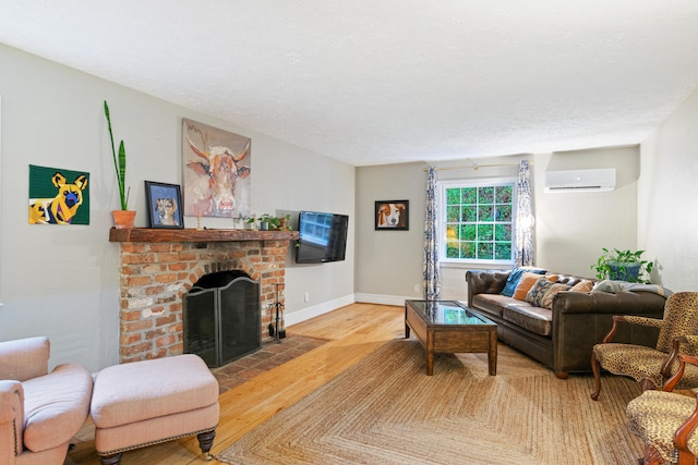 living room featuring a wall unit AC, wood-type flooring, a textured ceiling, and a brick fireplace