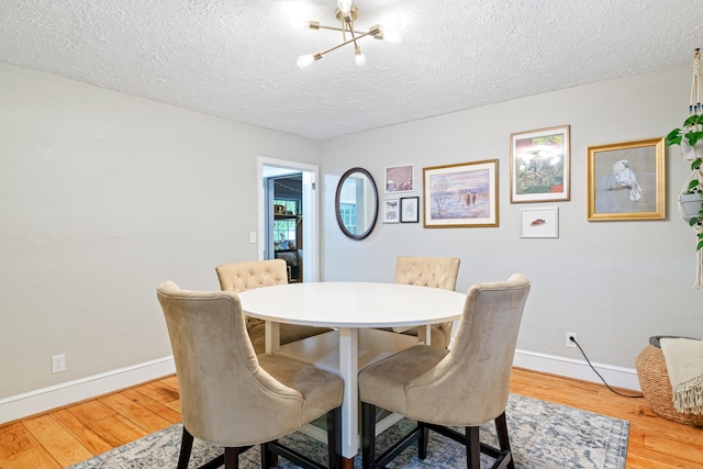 dining room featuring hardwood / wood-style floors, a textured ceiling, and a notable chandelier