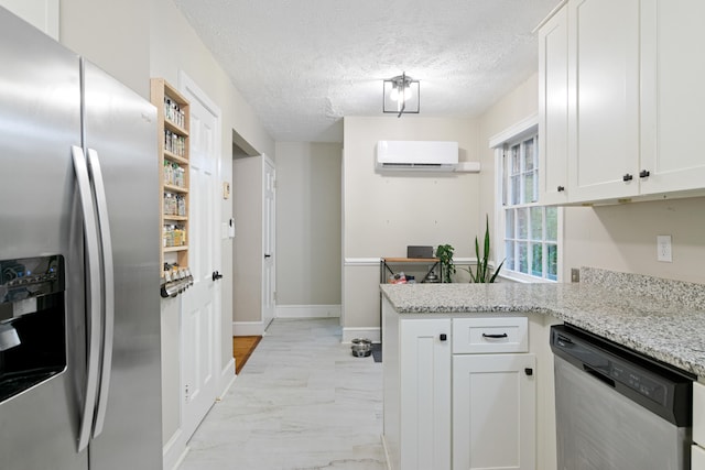 kitchen with light stone countertops, appliances with stainless steel finishes, a textured ceiling, a wall mounted AC, and white cabinets