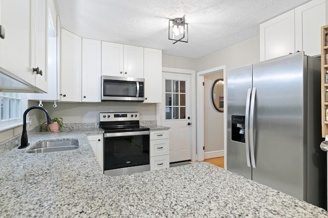 kitchen featuring a textured ceiling, white cabinetry, sink, and appliances with stainless steel finishes