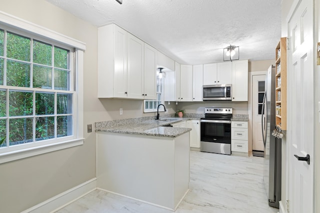 kitchen with white cabinetry, sink, light stone counters, a textured ceiling, and appliances with stainless steel finishes