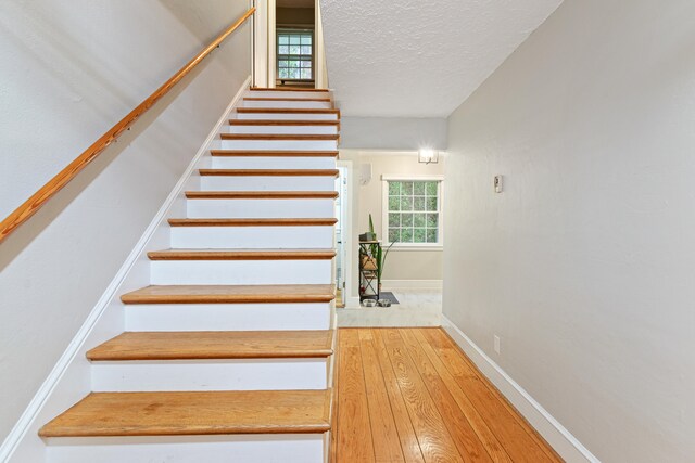 stairway with hardwood / wood-style floors and a textured ceiling