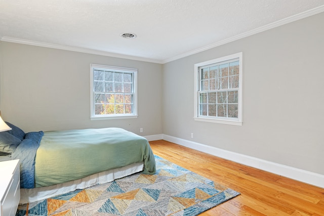 bedroom featuring crown molding, hardwood / wood-style floors, and a textured ceiling