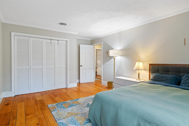 bedroom featuring a textured ceiling, wood-type flooring, ornamental molding, and a closet