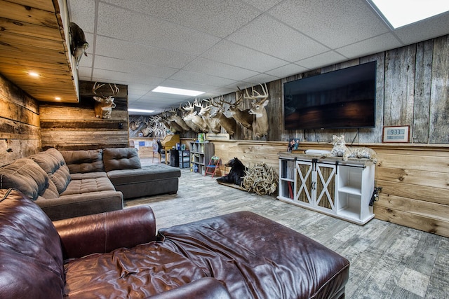 living room featuring hardwood / wood-style floors, a drop ceiling, and wood walls