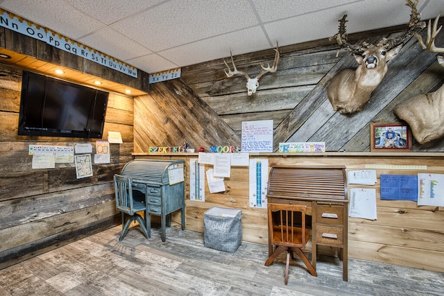 interior space featuring wood walls, a drop ceiling, and hardwood / wood-style flooring