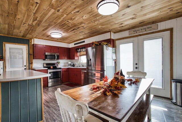 kitchen with wooden walls, plenty of natural light, and appliances with stainless steel finishes