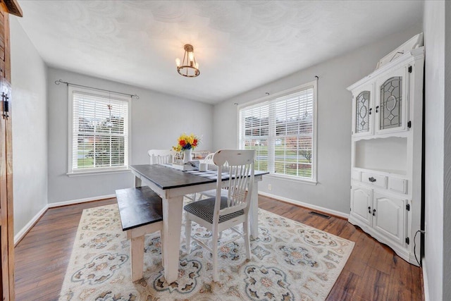 dining area with dark hardwood / wood-style flooring and a notable chandelier