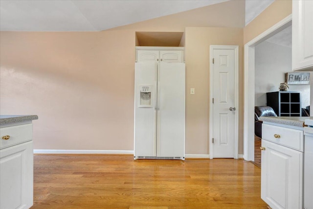 kitchen featuring white refrigerator with ice dispenser, light wood-type flooring, and white cabinetry