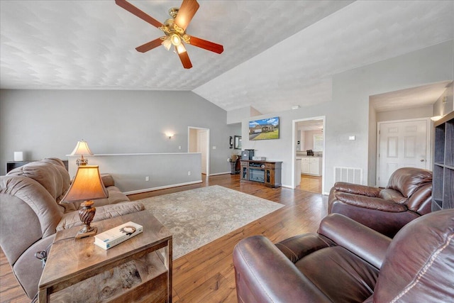 living room with ceiling fan, light wood-type flooring, and lofted ceiling