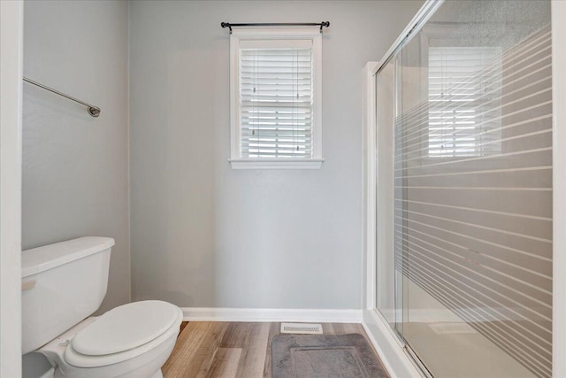 bathroom with toilet, a shower with shower door, and hardwood / wood-style flooring