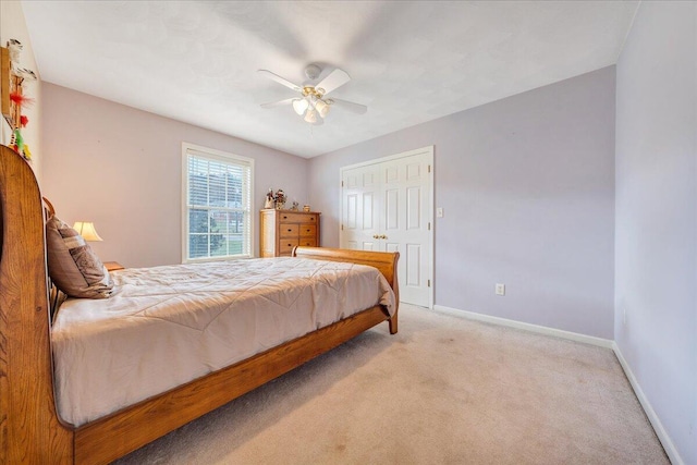 bedroom with a closet, ceiling fan, and light colored carpet