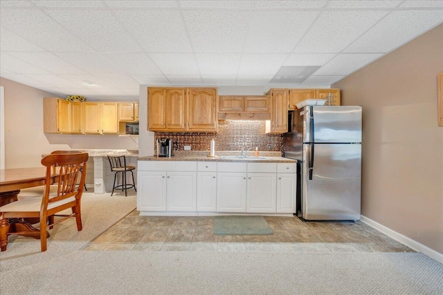 kitchen featuring light colored carpet, light brown cabinetry, stainless steel refrigerator, and tasteful backsplash