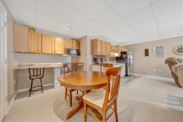 dining room with a drop ceiling and light colored carpet