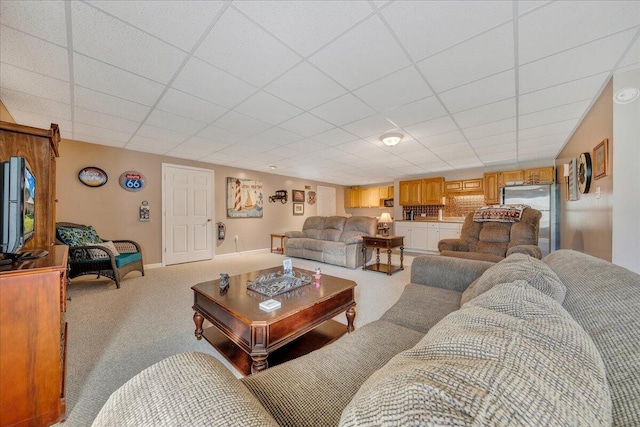 living room with a paneled ceiling and light colored carpet