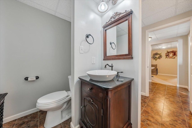 bathroom featuring tile patterned floors, a drop ceiling, toilet, and vanity