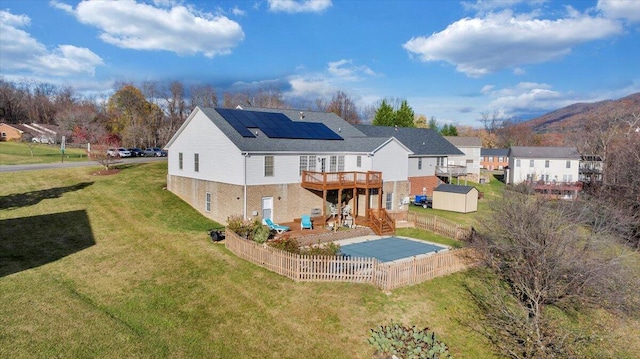 back of house featuring a lawn, solar panels, a shed, and a deck