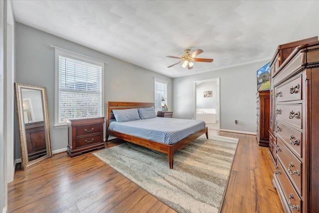 bedroom featuring light wood-type flooring, ensuite bath, and ceiling fan