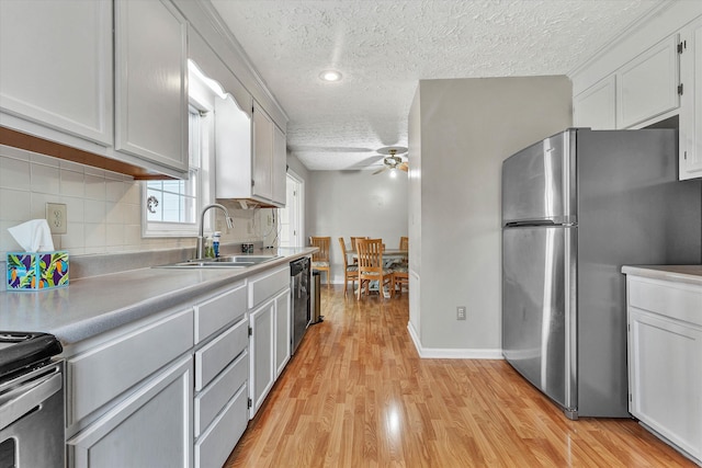 kitchen with white cabinetry, sink, ceiling fan, appliances with stainless steel finishes, and light wood-type flooring