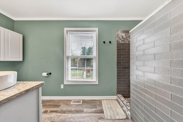 bathroom featuring a tile shower, vanity, and hardwood / wood-style flooring