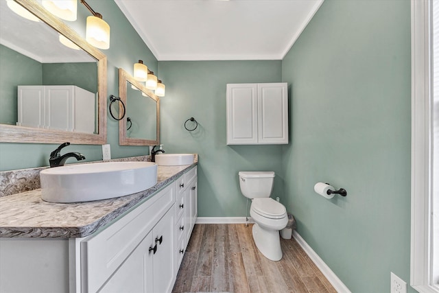 bathroom featuring toilet, vanity, wood-type flooring, and ornamental molding