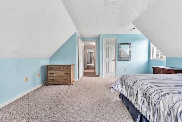 carpeted bedroom featuring a textured ceiling and vaulted ceiling