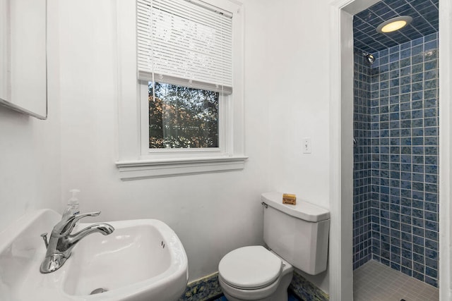 bathroom with sink, toilet, and tiled shower