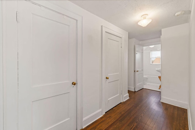 corridor with a textured ceiling and dark wood-type flooring