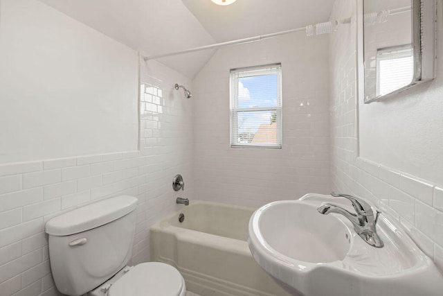 full bathroom featuring lofted ceiling, sink, tiled shower / bath combo, toilet, and tile walls