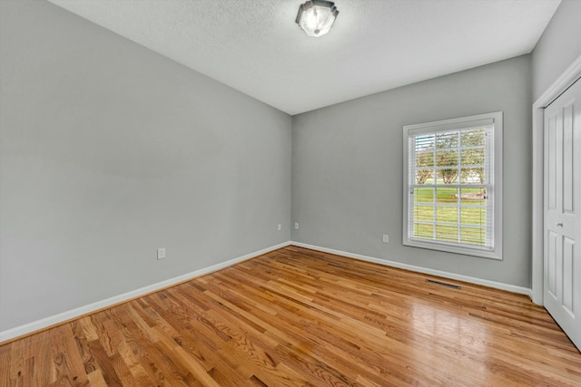 unfurnished bedroom with a closet, a textured ceiling, and light hardwood / wood-style flooring