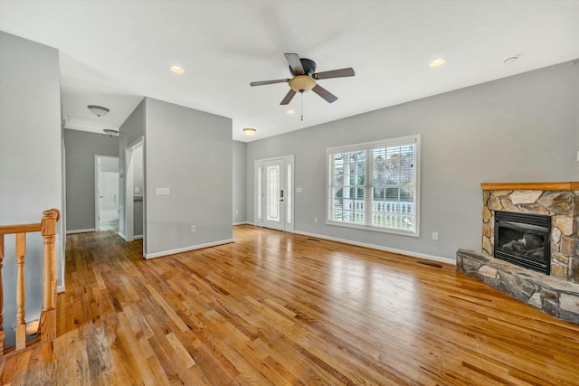 unfurnished living room featuring ceiling fan, a fireplace, and light hardwood / wood-style flooring